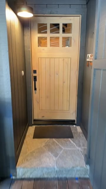 Warm outdoor entryway lighting fixture next to a wood front door