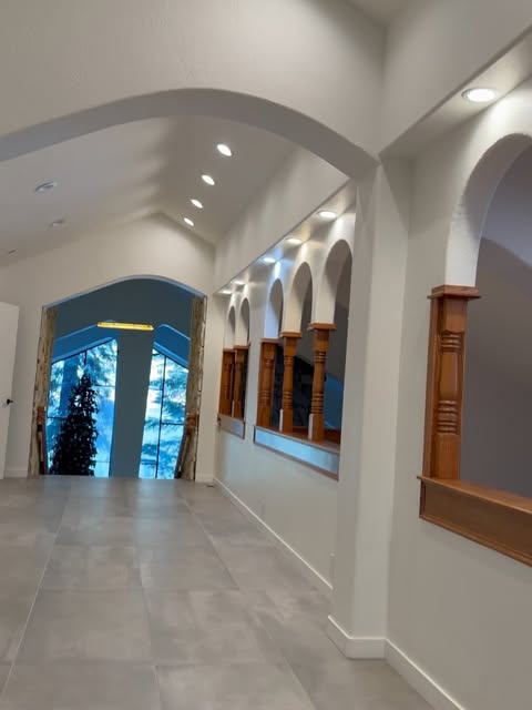 Recessed can lights along a vaulted hallway with wood arches